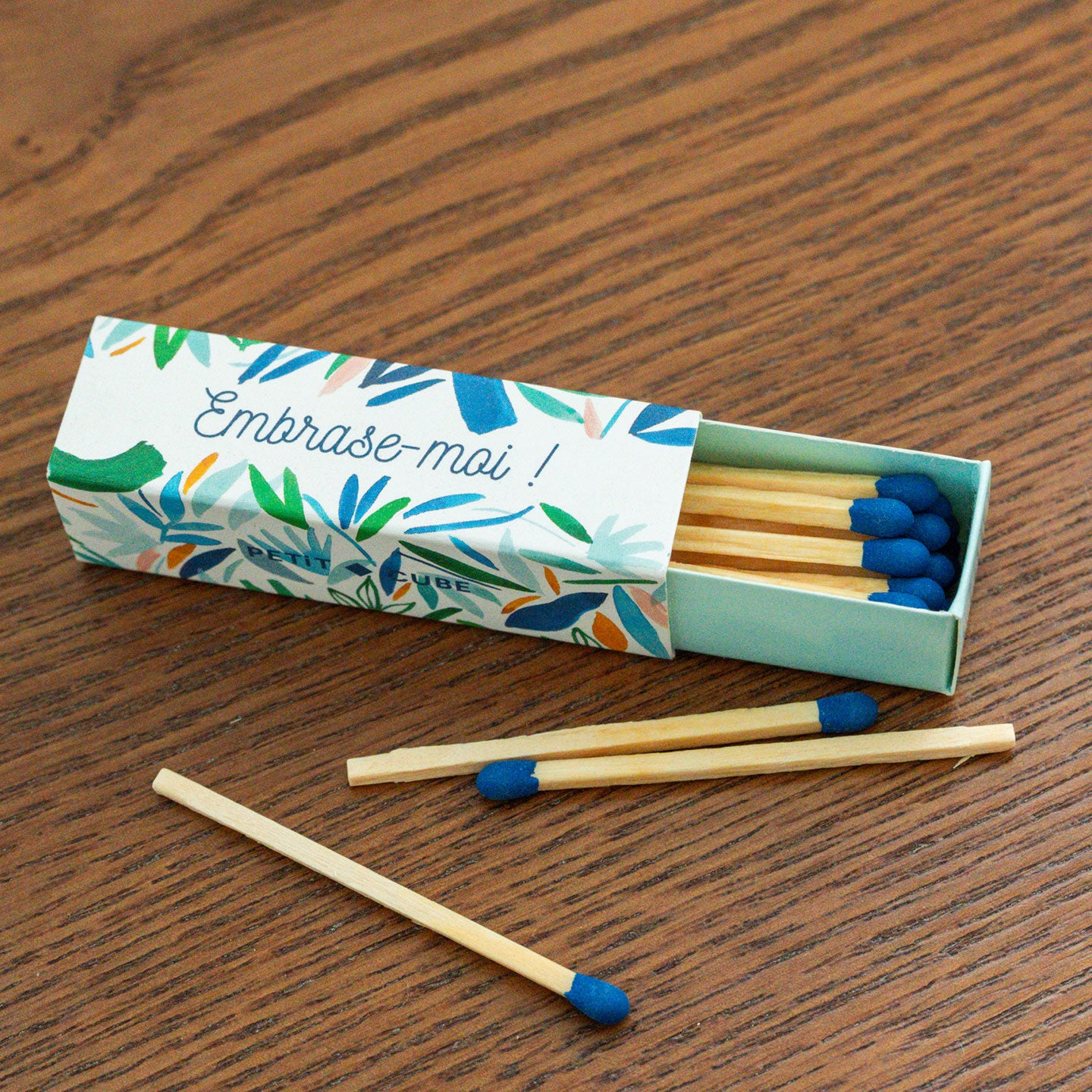 Boîte d'allumettes avec motif floral et message accrocheur.