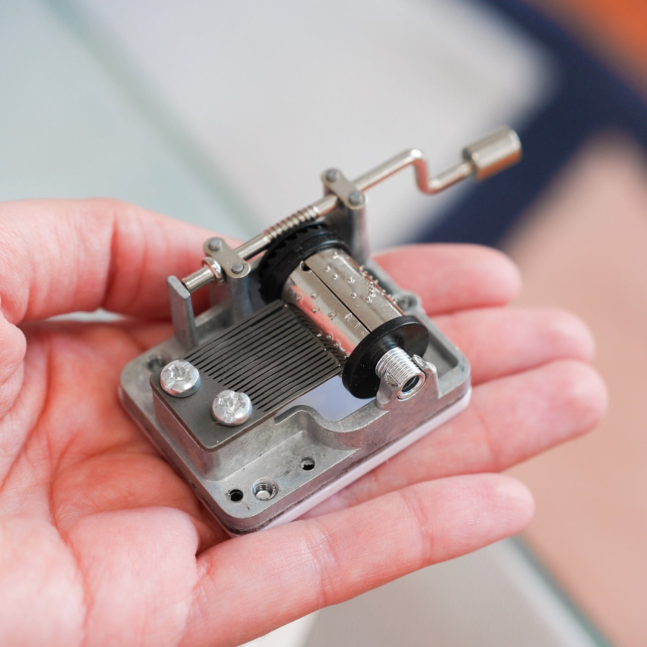 Boîte à musique avec manivelle, motif arc-en-ciel coloré.