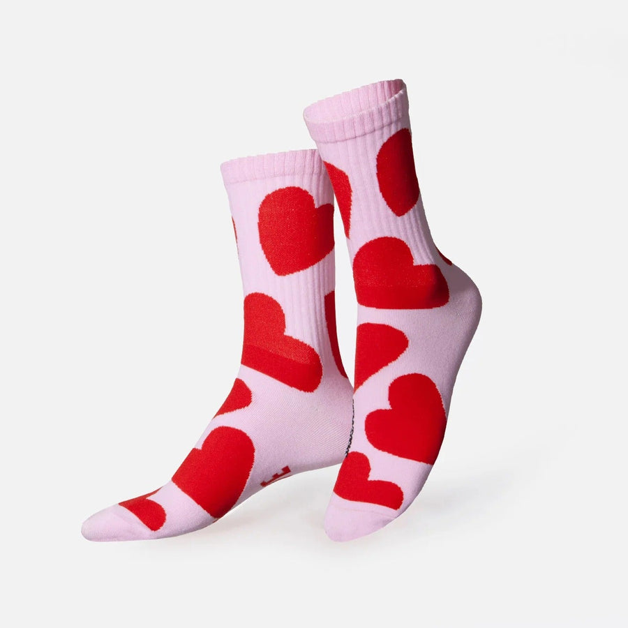 Chaussettes rose pâle ornées de grands cœurs rouges, présentées croisées