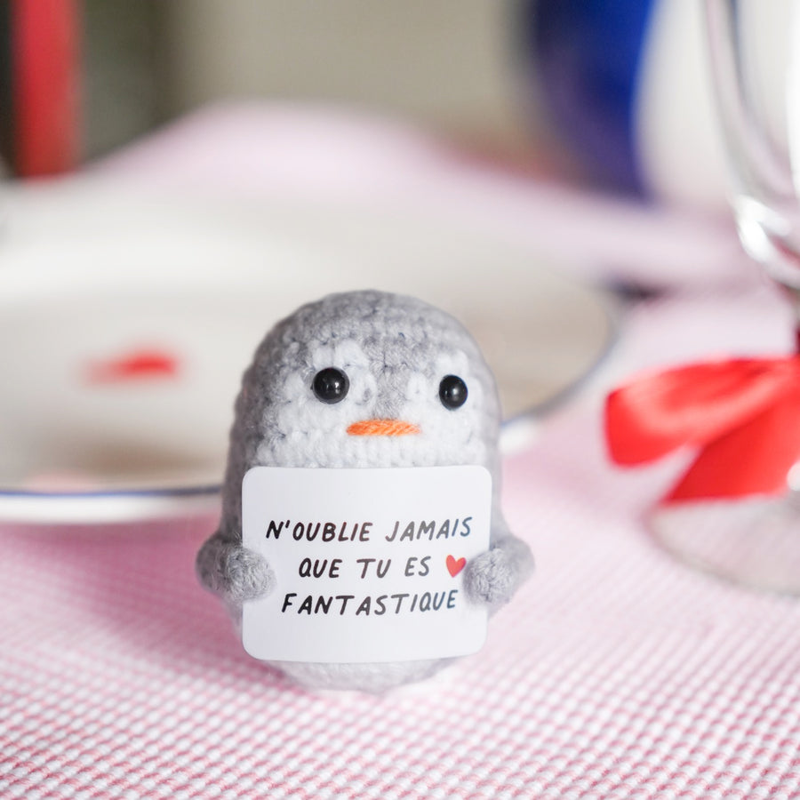 Peluche pingouin en crochet avec message inspirant sur son ventre.