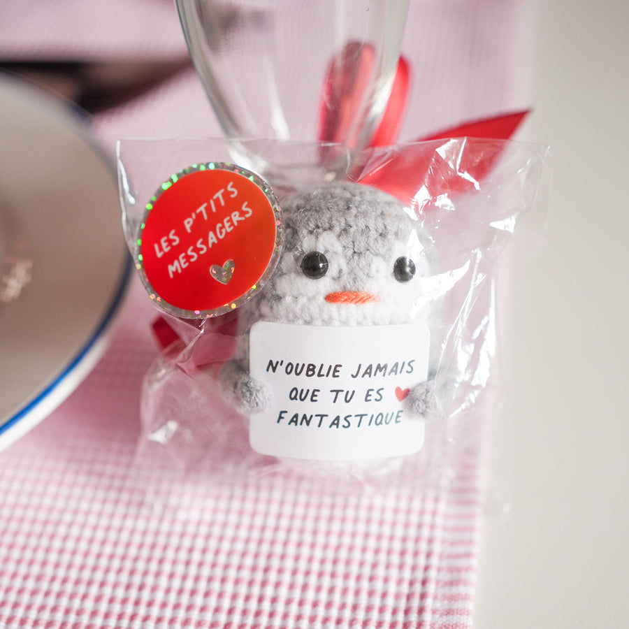 Peluche pingouin en crochet avec message inspirant sur les ailes.