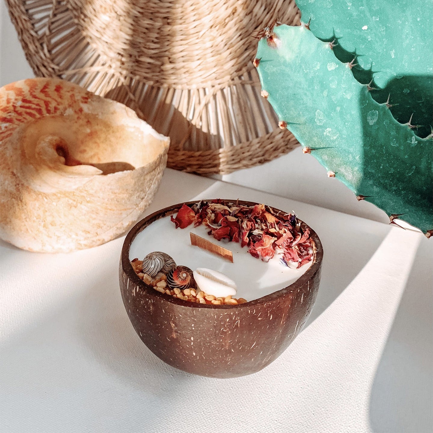 Bougie monoï dans une noix de coco avec fleurs séchées