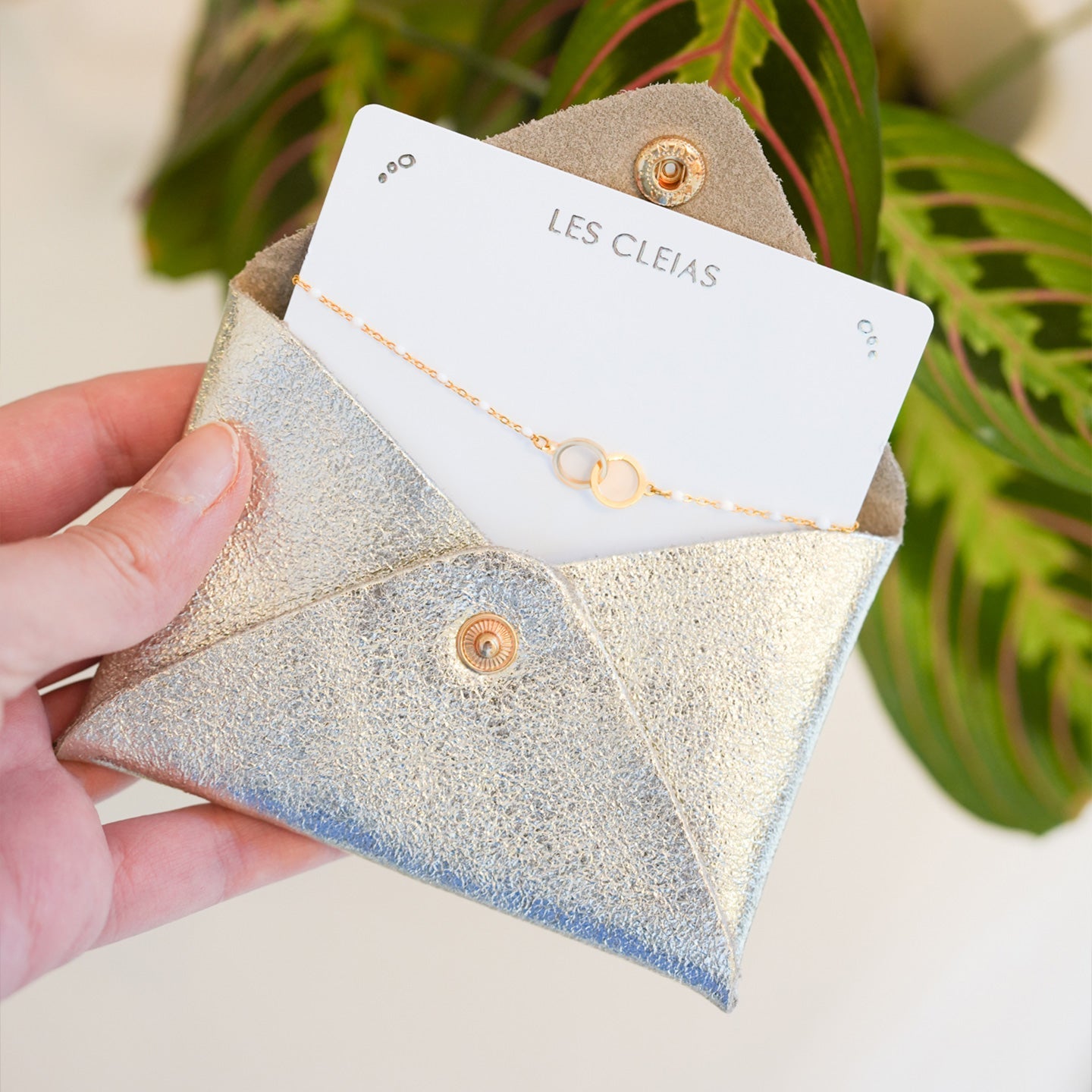Bracelet cercle blanc avec pochette en cuir doré, vue de près.