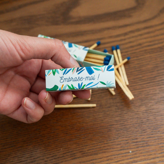 Boîte d'allumettes avec motif floral et message accrocheur.