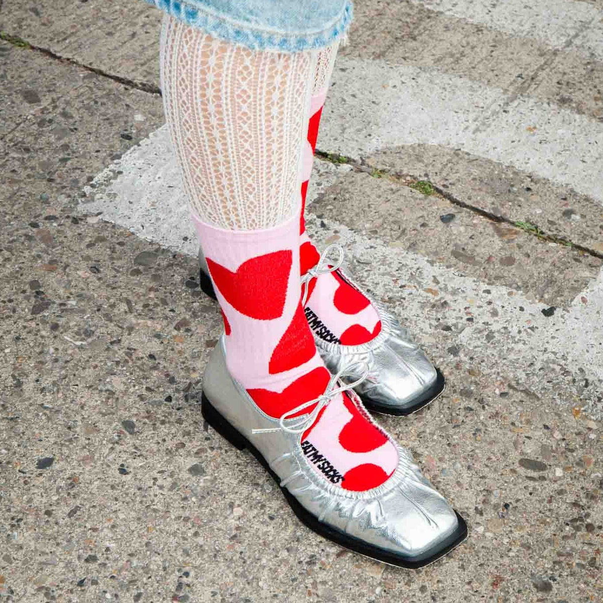 Chaussettes roses à grands cœurs rouges portées avec des ballerines argentées