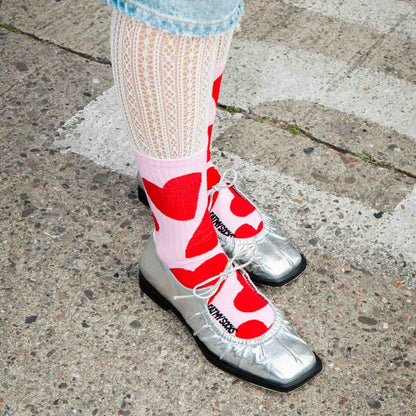 Chaussettes roses à grands cœurs rouges portées avec des ballerines argentées