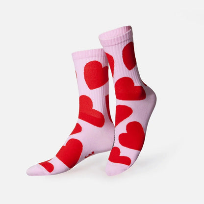 Chaussettes rose pâle ornées de grands cœurs rouges, présentées croisées