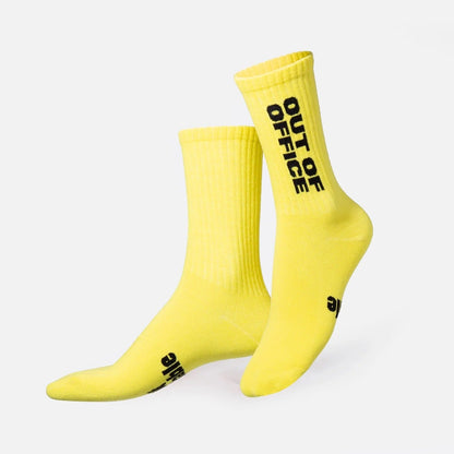 Paire de chaussettes jaunes côtelées, avec « OUT OF OFFICE » imprimé en noir