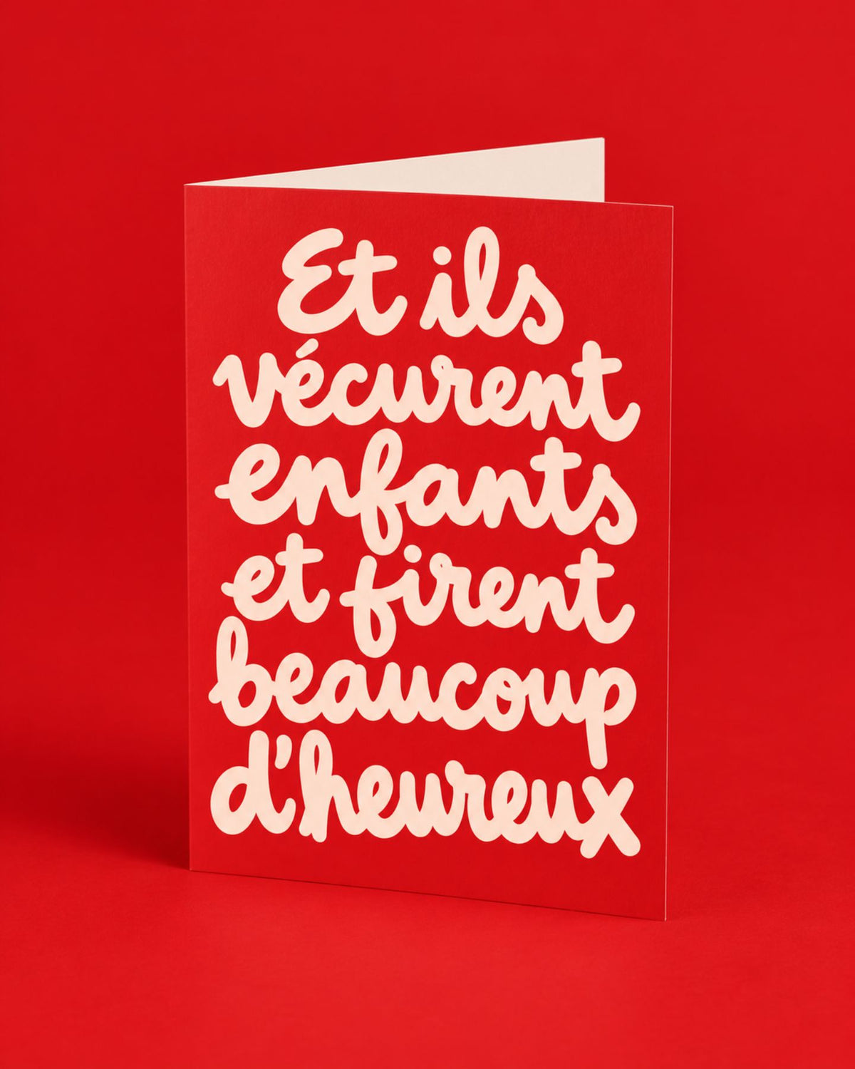 Carte rouge ouverte aux lettres manuscrites crème, photographiée de biais