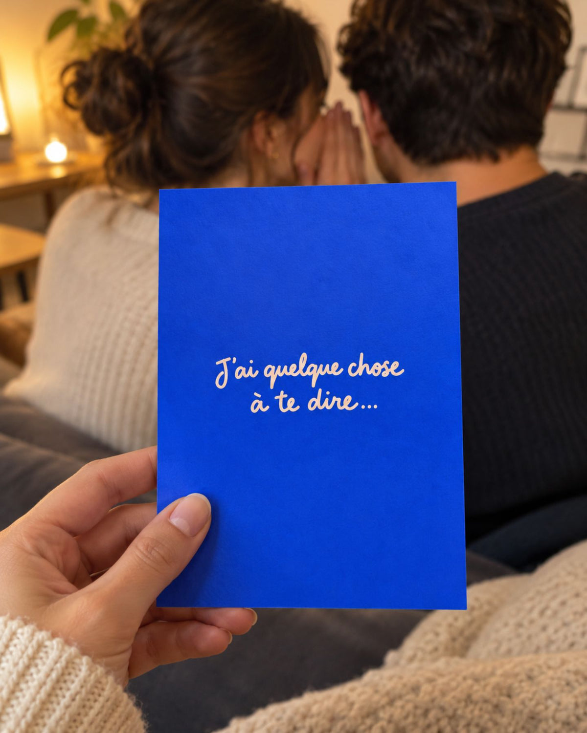 Carte bleu vif tenue devant un couple, avec un message en écriture manuscrite