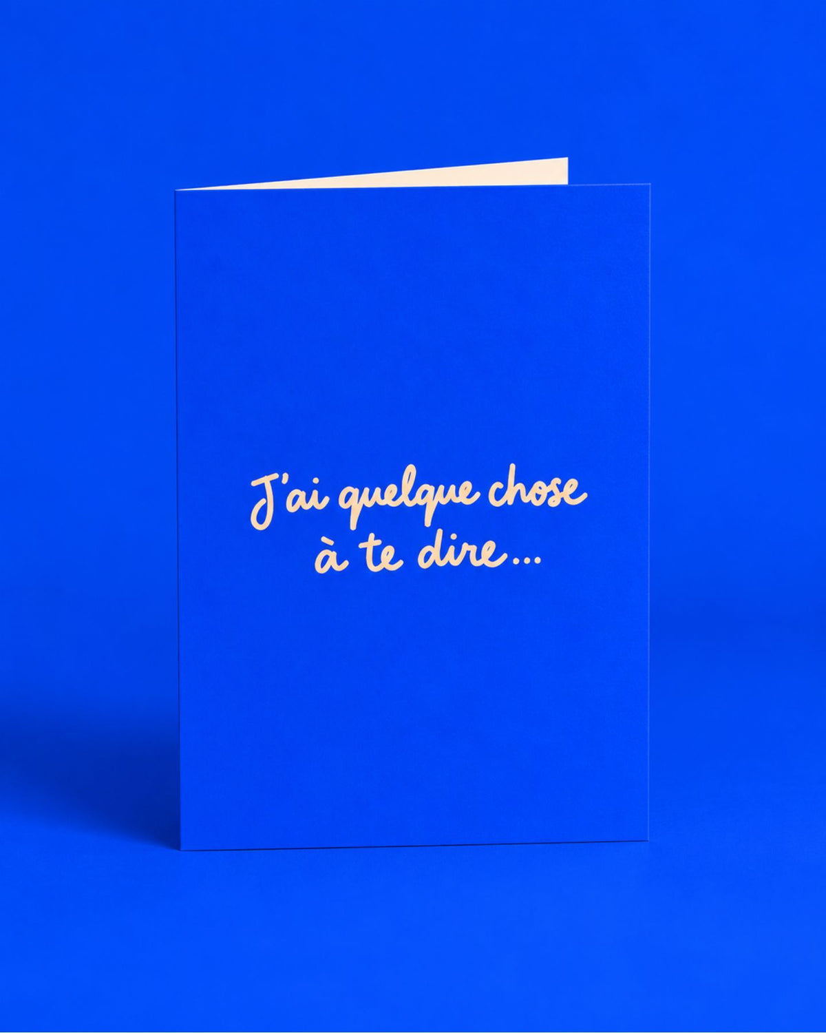 Carte bleue ouverte avec l’inscription manuscrite « J’ai quelque chose à te dire