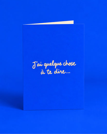 Carte bleue ouverte avec l’inscription manuscrite « J’ai quelque chose à te dire