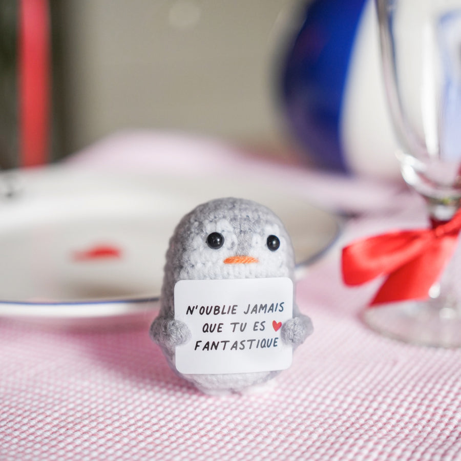 Peluche pingouin en crochet avec message inspirant sur son ventre.