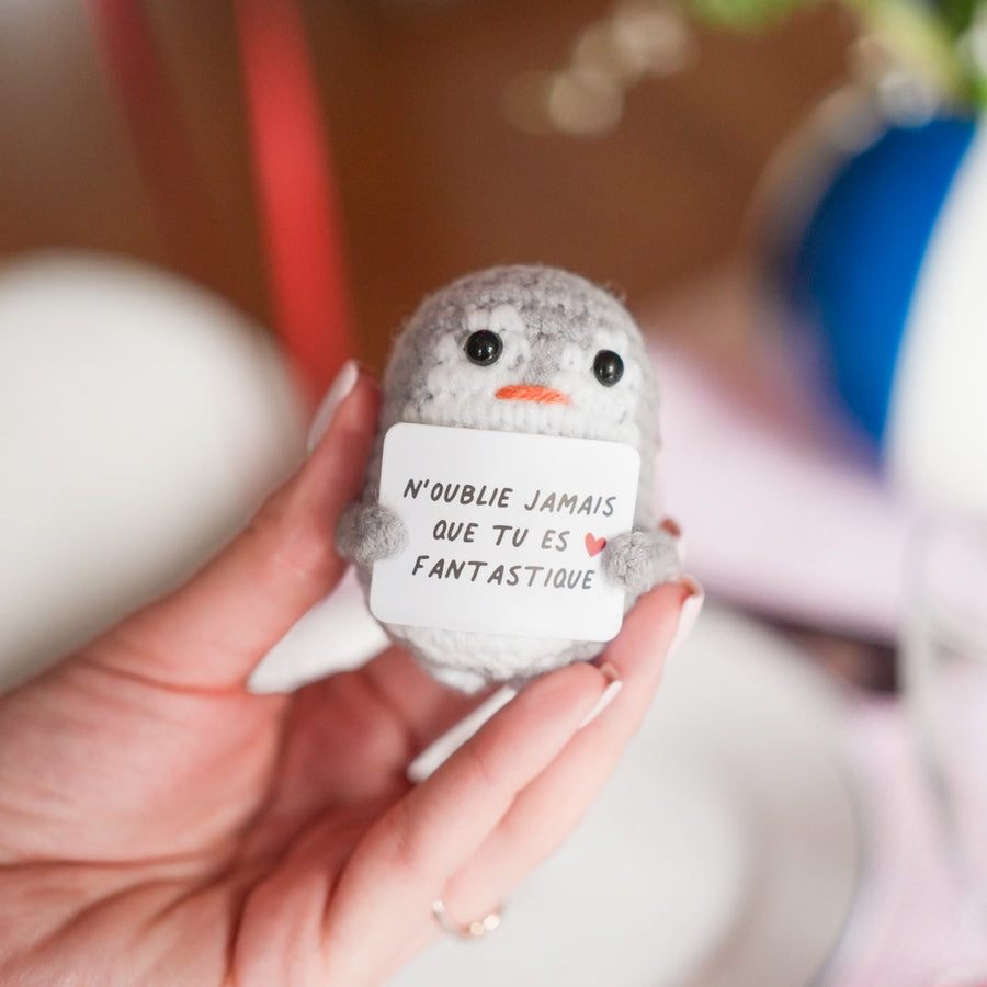 Peluche pingouin en crochet avec message inspirant sur son ventre.